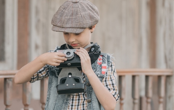 Мальчик в кепке с фотоаппаратом в руках