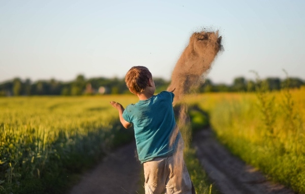 Мальчик бросает песок на дороге