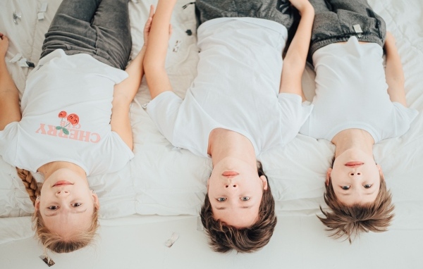 Дети в белых футболках лежат на кровати