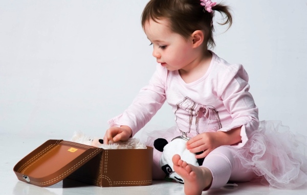 Девочка в розовом наряде с маленьким чемоданом