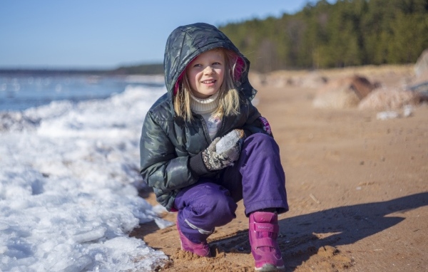 Девочка сидит у замерзшего озера 
