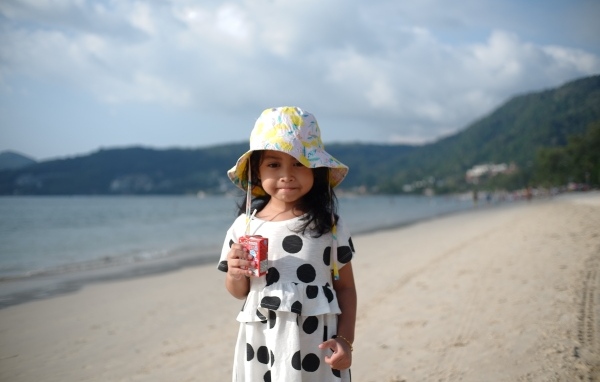 Девочка с соком в руках стоит на пляже