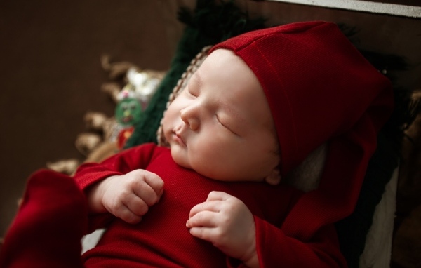Маленький ребенок спит в красном костюме