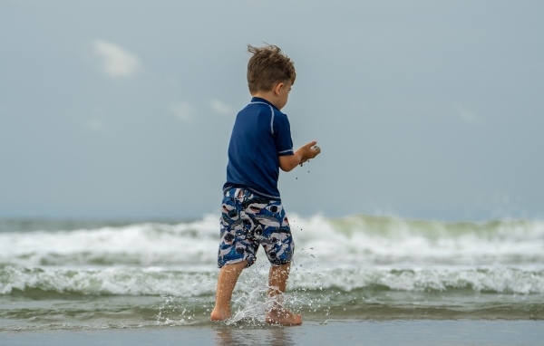 Маленький мальчик гуляет по морскому берегу