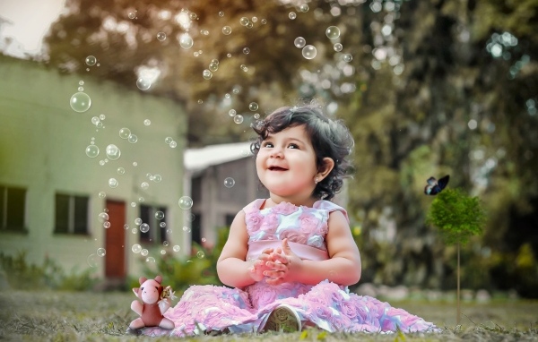 Маленькая девочка радуется мыльным пузырям