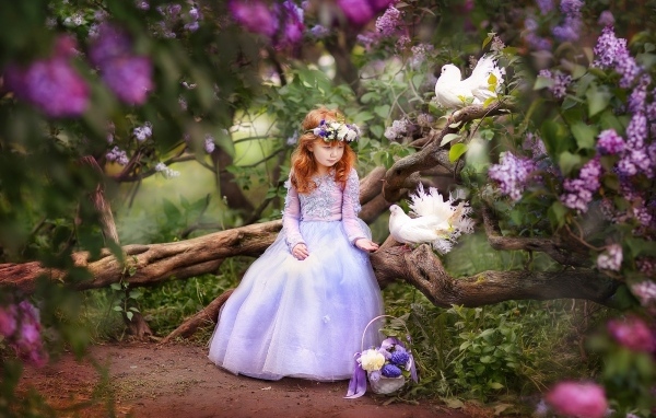 Маленькая девочка в красивом платье на дереве с голубями