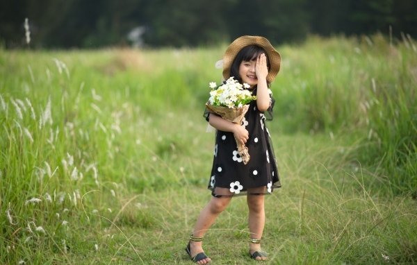 Маленькая девочка с букетом цветов на зеленой траве