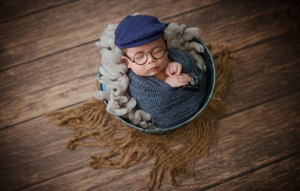 Маленький новорожденный ребенок в очках и кепке 