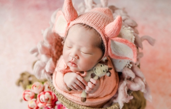 Маленький спящий новорожденный ребенок в шапке с рогами