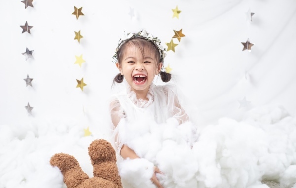 Маленькая улыбающаяся девочка азиатка в белом платье