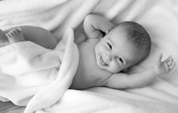 Маленький улыбающийся ребенок в белом покрывале