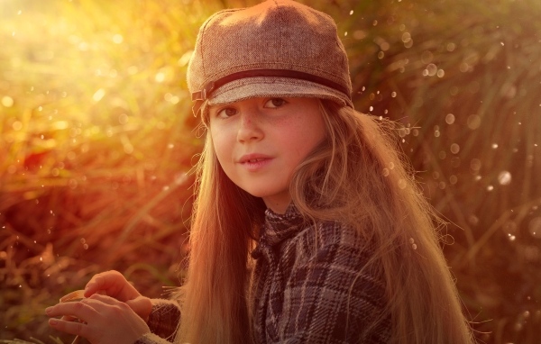 Длинноволосая девочка в кепке в лучах солнца