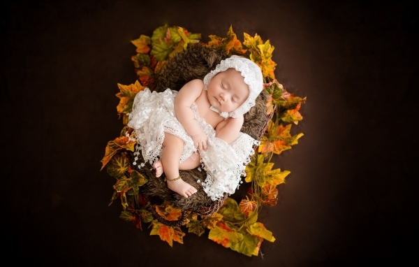 Новорожденная девочка в колыбели в белом костюме