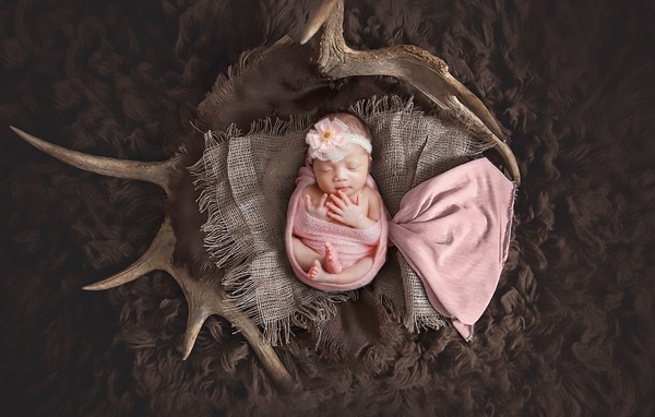 Новорожденная девочка на покрывале с рогами