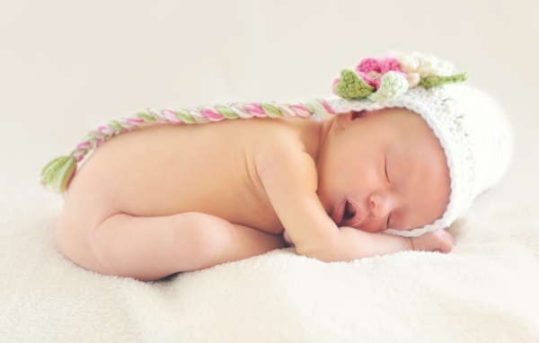 Новорожденная девочка спит в шапке