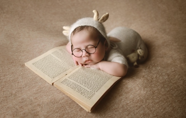 Новорожденный ребенок спит с книгой