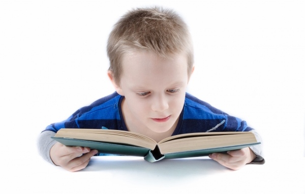 Школьник читает книгу на белом фоне