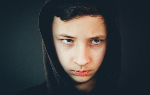 Серьезный мальчик в черном капюшоне