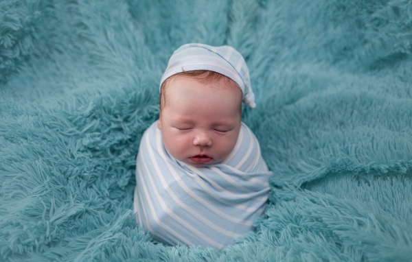 Спящий новорожденный малыш на голубом покрывале 