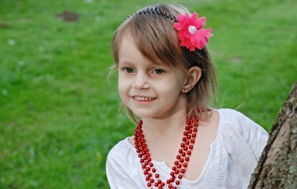 Улыбающаяся девочка стоит у дерева