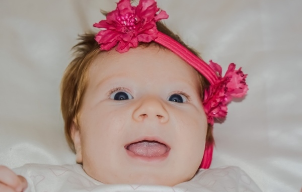Улыбающаяся маленькая девочка с цветком на голове