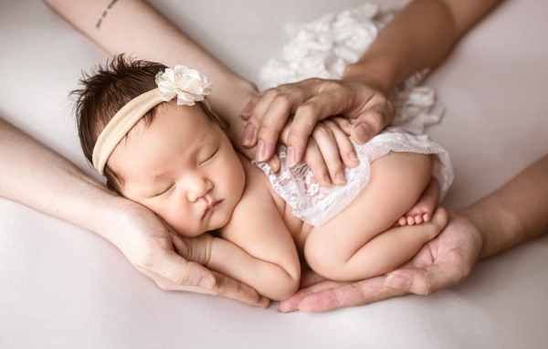 Руки родителей оберегают спящего малыша