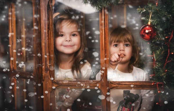 Две маленькие девочки сидят у окна на Рождество