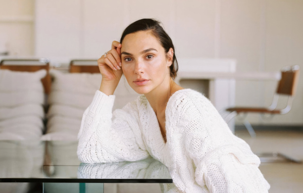 Актриса Галь Гадот в белом свитере за столом