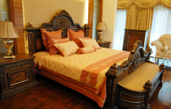 Большая деревянная кровать в спальне с оранжевым интерьером