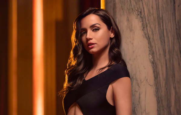 Длинноволосая актриса Ана де Армас стоит у стены