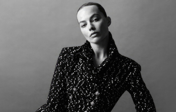 Грустная Марго Робби в блестящем пиджаке на сером фоне