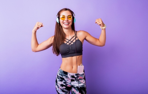 Улыбающаяся спортивная девушка слушает музыку