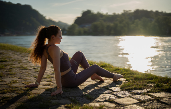 Спортивная девушка сидит на берегу реки