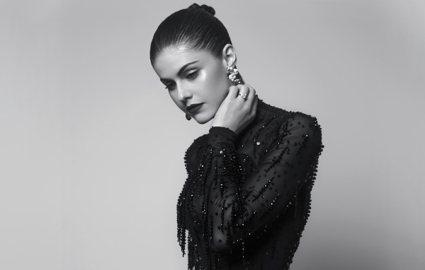 Молодая актриса Александра Даддарио в черном платье на сером фоне