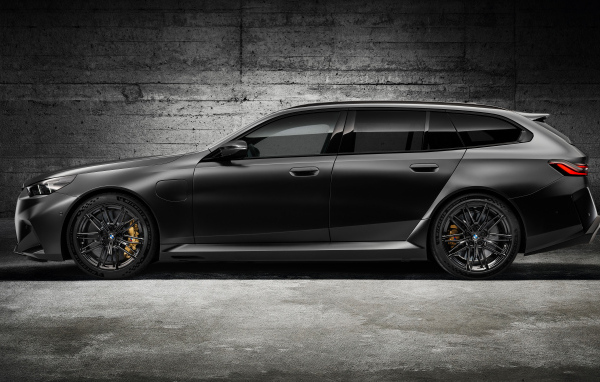 Вид сбоку на черный автомобиль BMW M5 Touring 2024 года