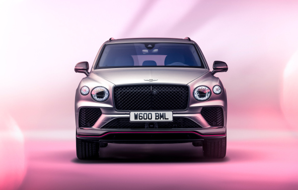 Вид спереди на автомобиль Bentley Bentayga V8 S Curated By Mulliner 2024 года на розовом фоне