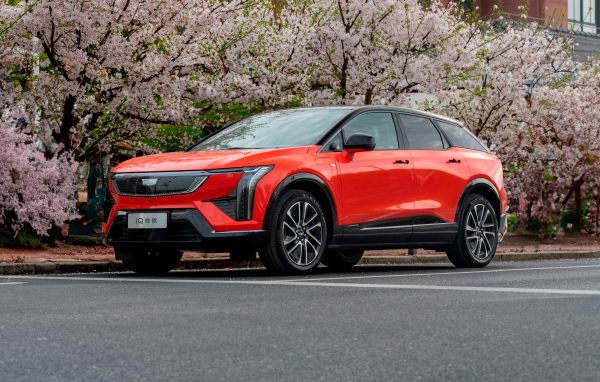 Красный Cadillac Optiq Sport 2024 года у цветущих деревьев