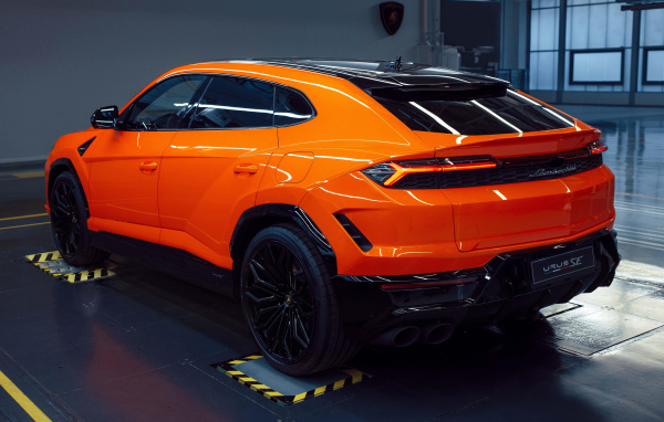 Вид сзади на оранжевый автомобиль  Lamborghini Urus SE Plug-In Hybrid 2024 года