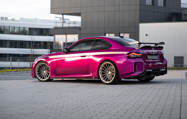 Вид сзади на розовый автомобиль Manhart MH2 GTR II 2024 года