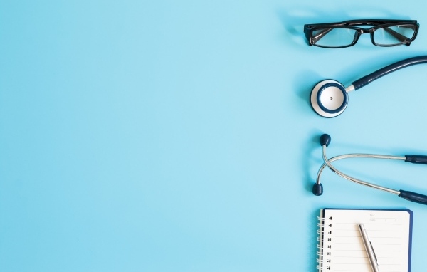 Стетоскоп, очки и блокнот на голубом фоне