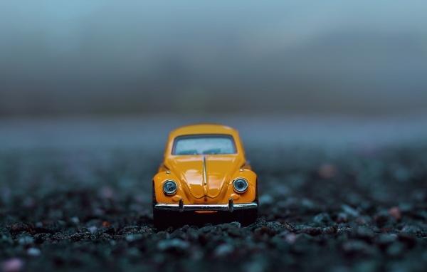 Маленькая игрушечная машинка стоит на асфальте