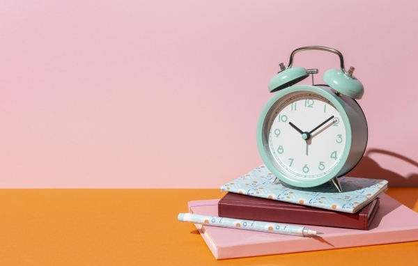 Будильник с книгами на розовом фоне