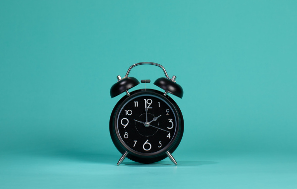 Черный будильник на голубом фоне