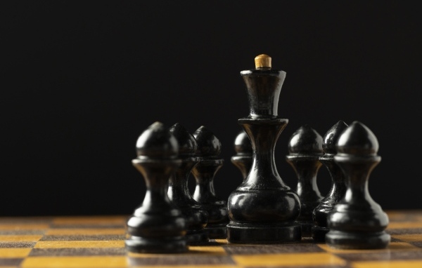 Черные шахматные фигуры на доске на черном фоне