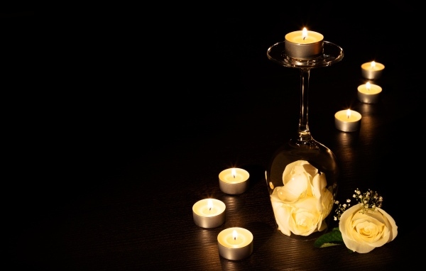 Зажженные свечи с цветами розы на черном фоне