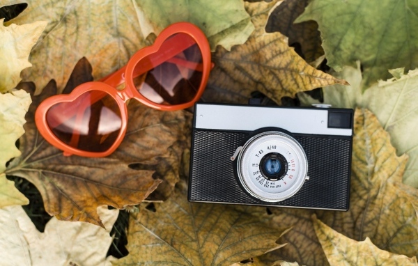Фотоаппарат с очками на опавшей листве