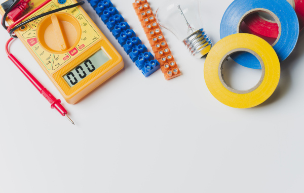 Электрическические приборы, мультиметр, изолента на сером фоне