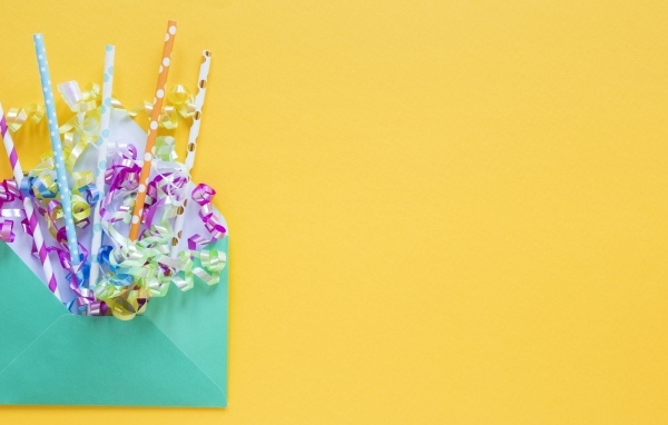 Конверт с трубочками и лентами на желтом фоне