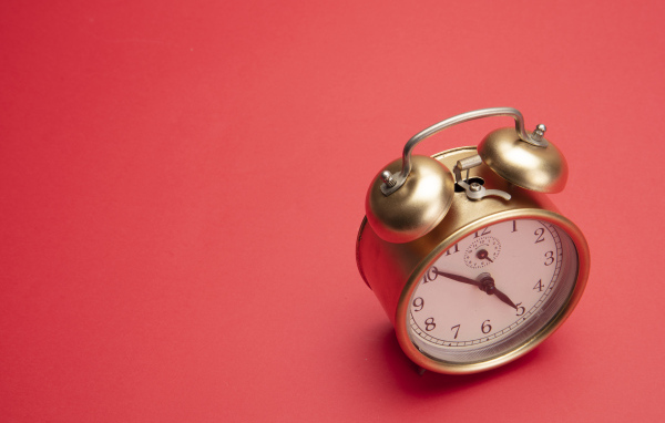 Золотой будильник на красном фоне