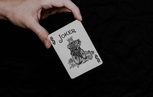 Карта Джокер в руке на черном фоне